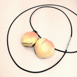a light orange and coral coloured peach locket open. stung onto a faux leather cord 1mm